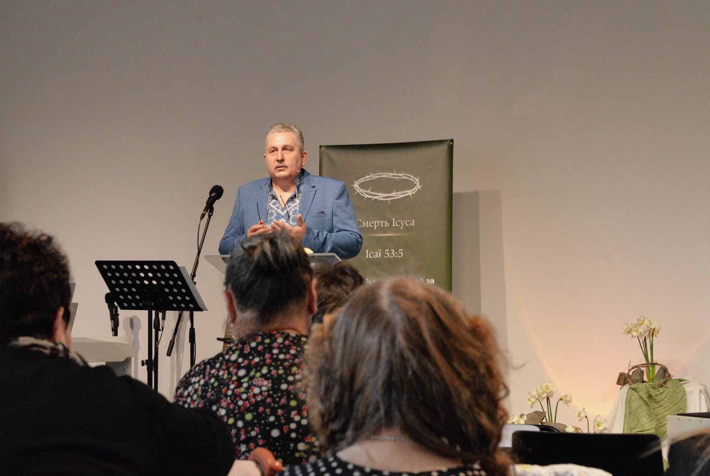The pastor preaching at the Sunday service, people listening in the hall